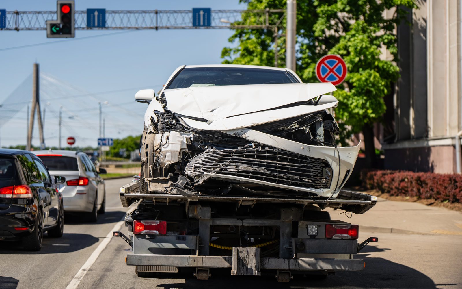 Samochód z rozbitym przodem przewożony na lawecie w ruchu ulicznym